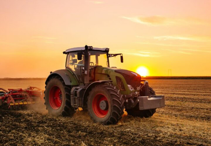 tractor harvesting with the sun in the background